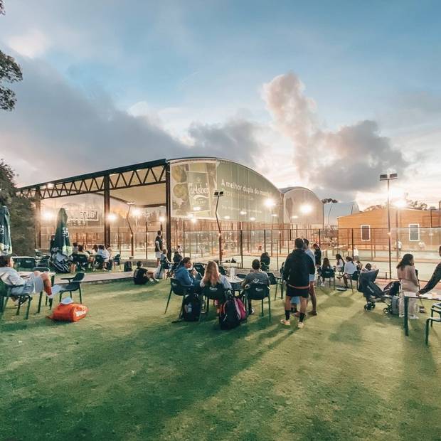 Players and spectators on the lawn at W Padel Country Club at sunset